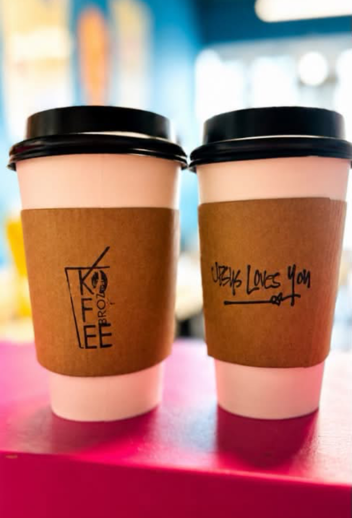 Two hot 12 oz cups with Kofee Broz and Jesus Loves You sleeves