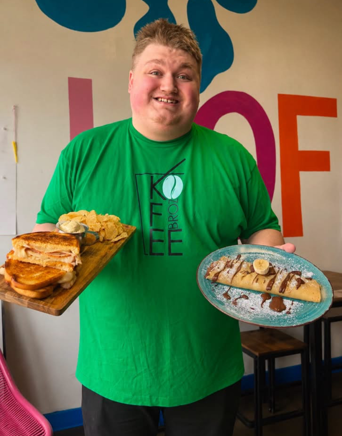 Team member serving a pesto chicken sandwich and Nutella banana crepe